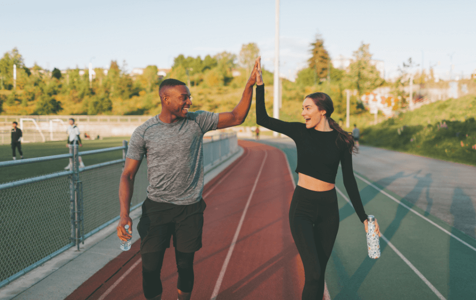 Two people high-fiving on a running track