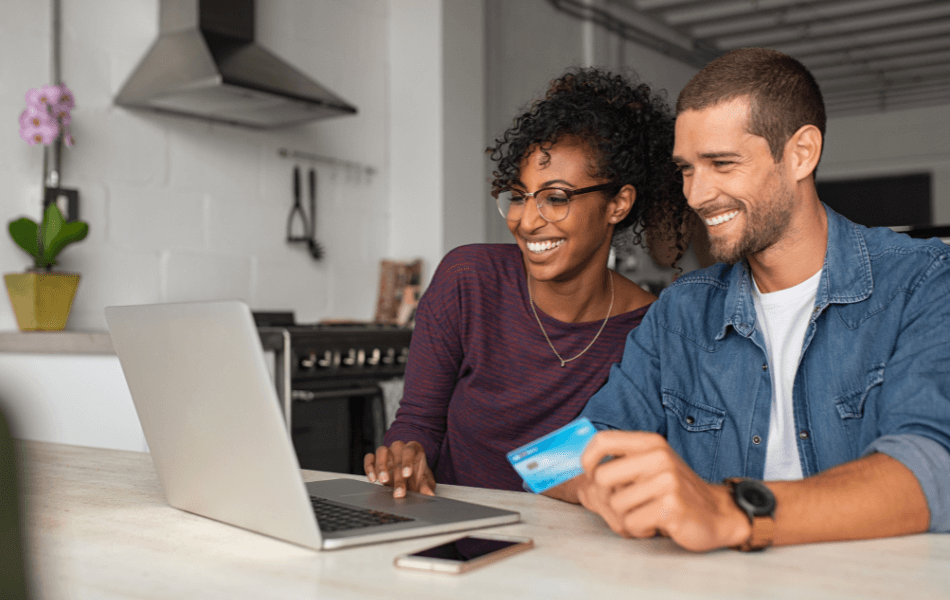 Two people looking at a laptop with one of them holding a credit card