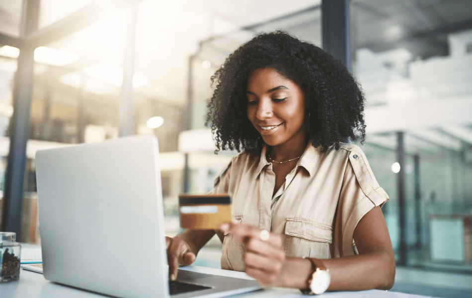 Person holding a credit card and on a laptop