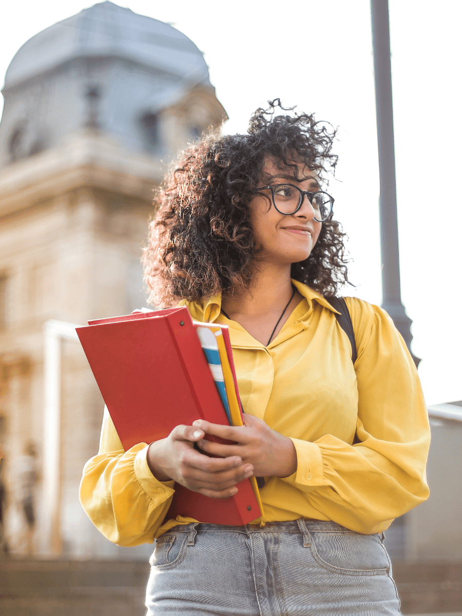 Girl in a yellow blouse holding notebooks